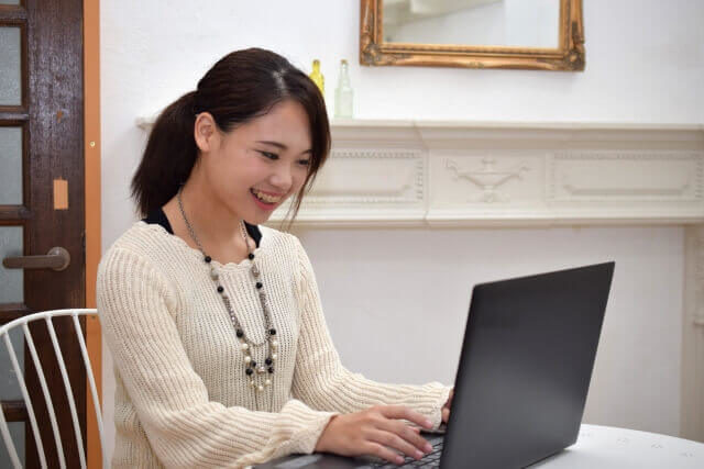 笑顔でパソコンをうつ女性