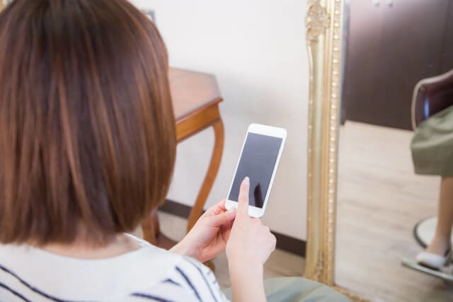 スマホを操作する女性の後ろ姿